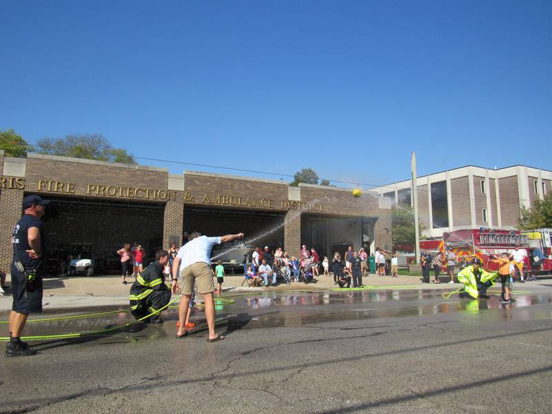 Firefighters provide guidance to kids as they fight to get the ball over their opponents' line.