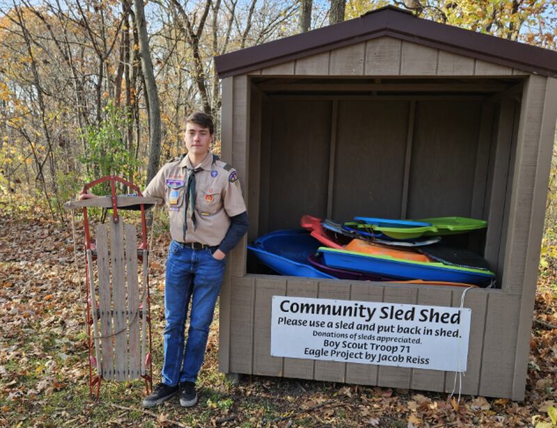 Genoa Boy Scout Jacob Reiss poses next to a community sled shed he built as part of his Eagle Award project. The shed is at Russell Woods Forest Preserve and the sleds are available to all.
