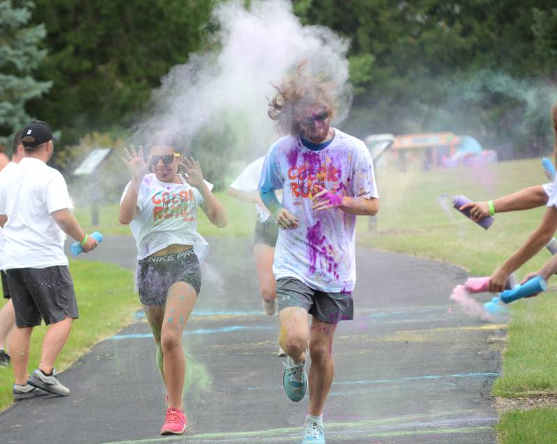 Ian Hussung runs with Kollins and Arayn Anaya through one of the color stations at the Oregon Park District's color run on Tuesday, July 30, 2024. Runners and walkers got doused with powdered colors as they made their way along the course at Oregon Park West.
