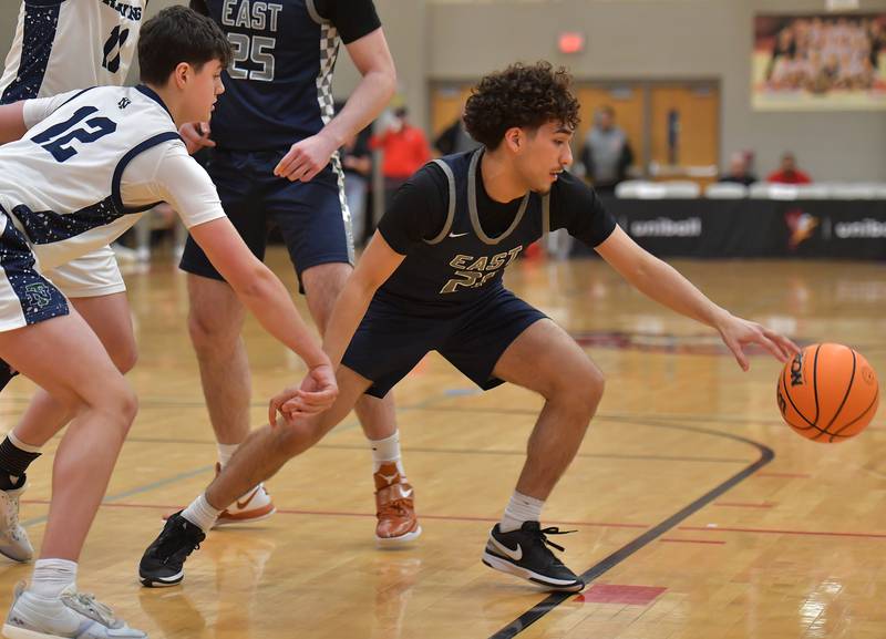 Oswego East’s Juan Zavala reaches for a loose ball in front of New Trier’s MJ Burns (12) during a When Sides Collide Shootout game on January 24, 2026 at Benet Academy in Lisle.