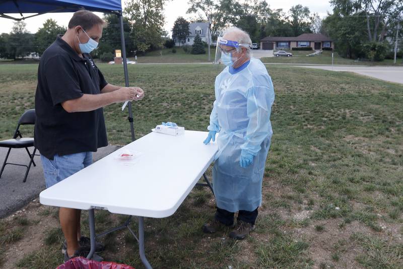 Ed Jost, left, prepares to have a COVID-19 test sample collected by Curative Testing Specialist Tod Schneider at the weekly COVID-19 testing site for McHenry School District 15 staff on Monday, Sept. 20, 2021, at Hilltop Elementary School in McHenry.