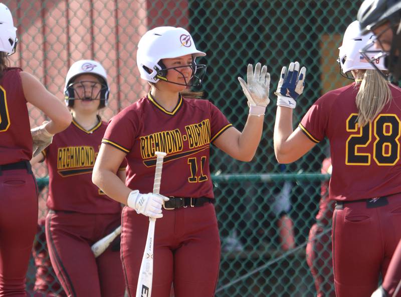 Richmond-Burton’s Sydney Hird, center, greets teammates during an early Rocket rally in varsity softball at Marengo Tuesday.