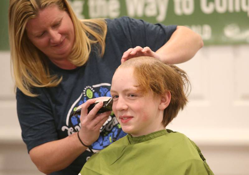 Waltham Scout James Lowery, has his head shaved by beautician Sarah Stewart of Downstairs on 1st Day Spa during the 18th annual Illinois Valley Emergency Services St. Baldrick's event on Sunday, March 23, 2025 at Senicas Oak Ridge in La Salle.