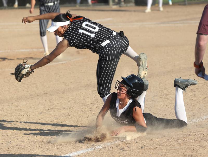 Prairie Ridge's Kylie Rosene slides in to third as the ball gets by Crystal Lake Central's Liv Shaw allowing Rosene to score Friday, June 6, 2025, during their Class 3A sectional final game at Sycamore High School.