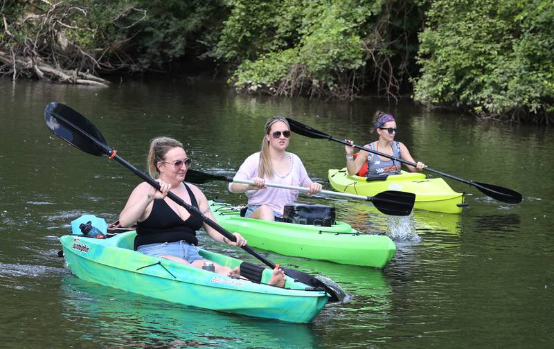 Kosova Gashi, (left) from Cortland, Heather Martines, from Genoa, and Blair Montoya-Wilkinson, (right) from Sycamore, paddle downstream in the Kishwaukee River Sunday, July 31, 2022, near David Carrol Memorial Citizens Park in Genoa.