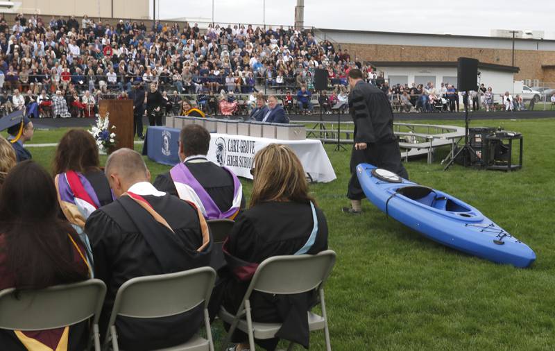 Cary-Grove Principal Neil Lesinski retrieves his speech from his kayak during the graduation ceremony for the class of 2023 at Cary-Grove High School in Cary. He was talking about how impressed he was with the students creativity on Anything but a Backpack Day at school.
