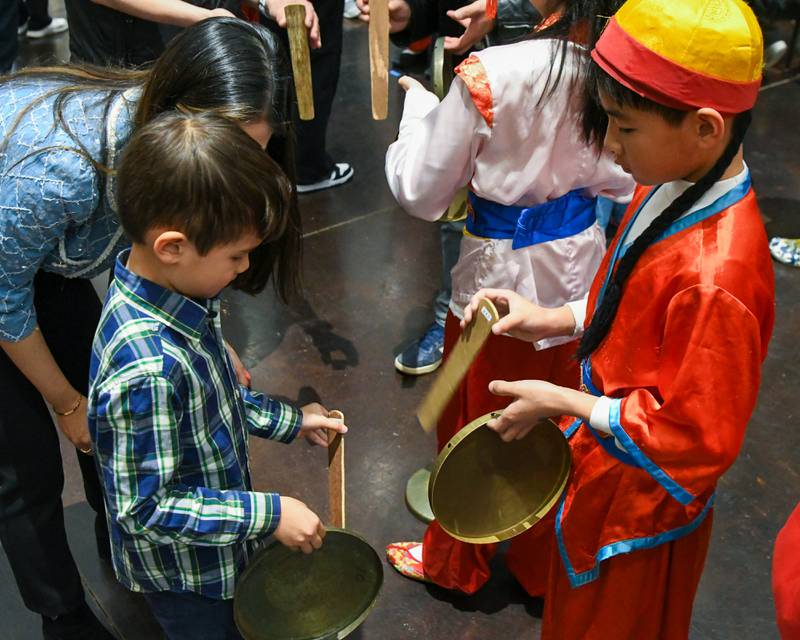 George Manson,5, left, of Northbrook along with his mom Dora Chang learn how to play one of the instruments as community members get to try the different instruments that were used during the performance from the Jhong Jheng Elementary School Suona And drum Ensemble from Kinmen, Taiwan, held at the Taiwanese American Chamber of Commerce building in Westmont.