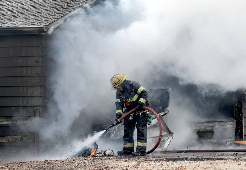 Peru firefighter Jake McKinney extinguishes buring debris while on the scene of a garage fire on Monday, Feb. 9, 2026 in the 1900 block of Shooting Park Road.