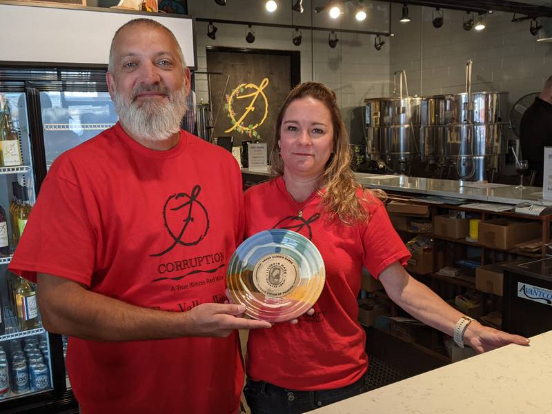 Fox Valley Winery owner Mike Faltz, left, and his wife, Leslie, right, display the certification from the Illinois Department of Tourism naming the business an Illinois Made business.