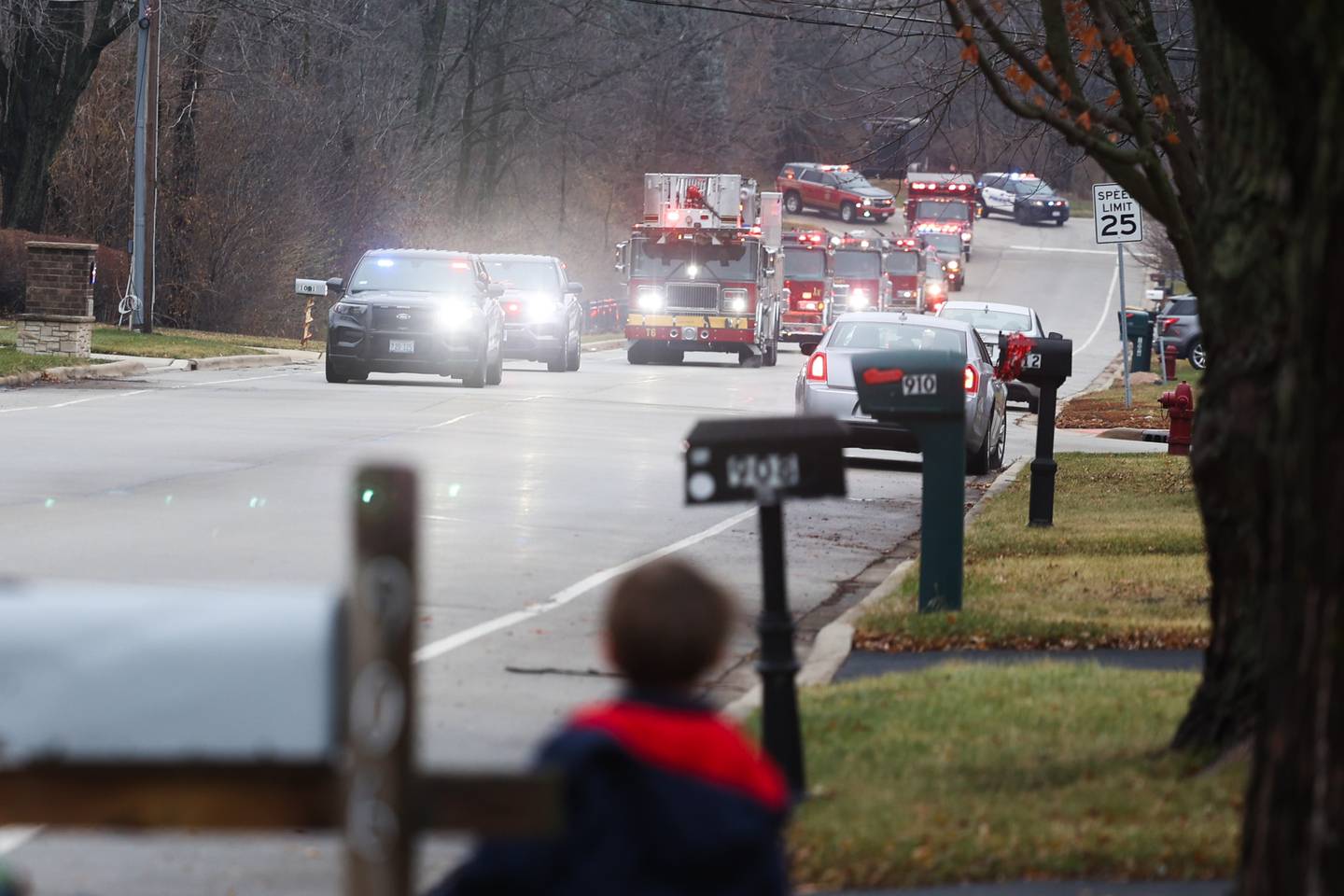 Gage Jenicek, 5, watches as a parade of Lockport police, fire department and volunteer vehicles come to deliver gifts to the Jenicek family on Saturday, Dec. 10, 2022, in Lockport.