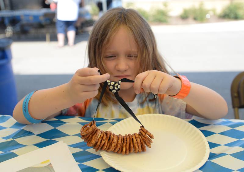 Children including Maggie Broomhead of Downers Grove make pretzel necklaces during the District 58 Oktoberfest held Saturday Sept 17, 2022.