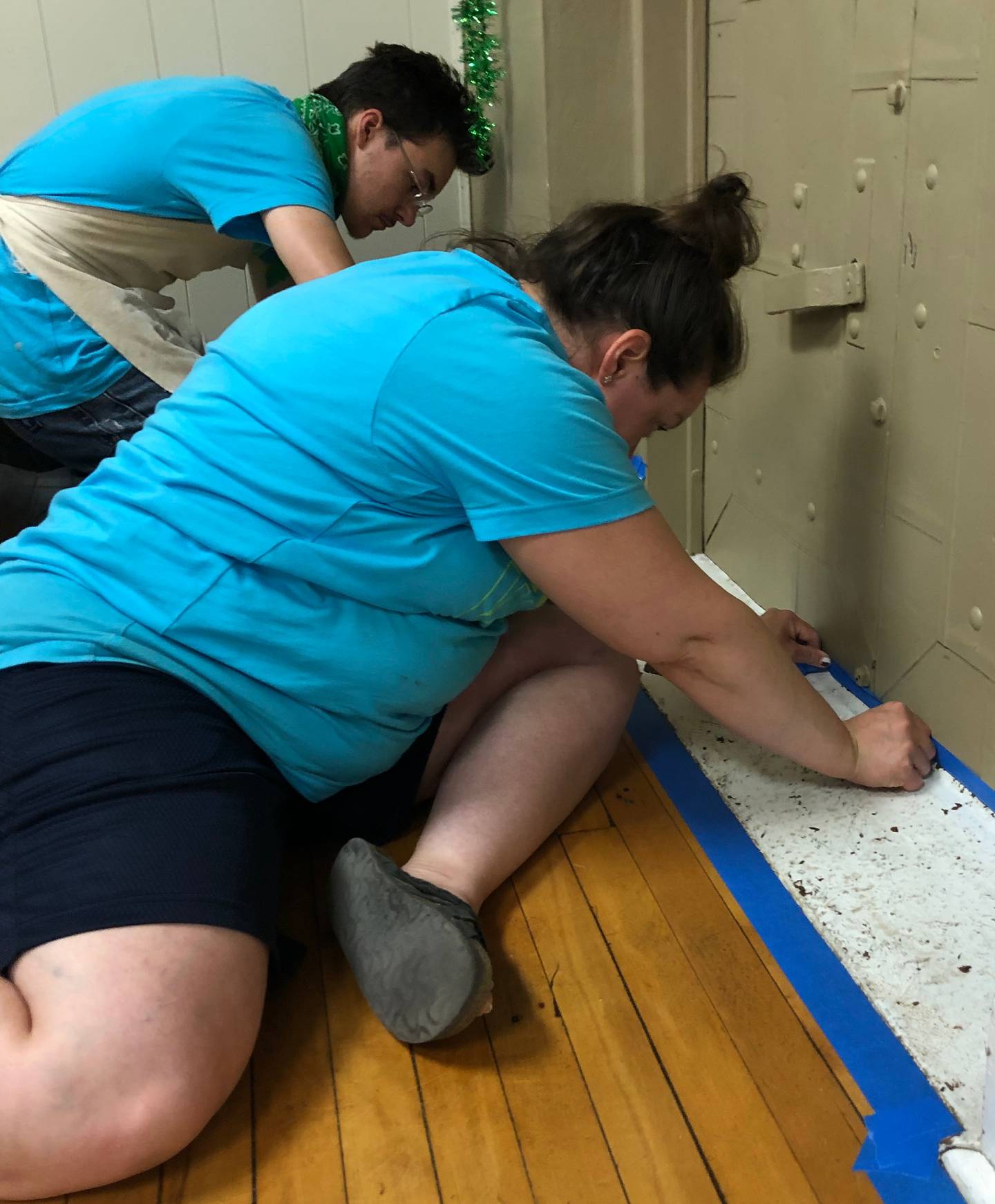 Hope Week volunteers tape the trim in the Putnam County Community Center to prepare it for painting on Wednesday, June 8.