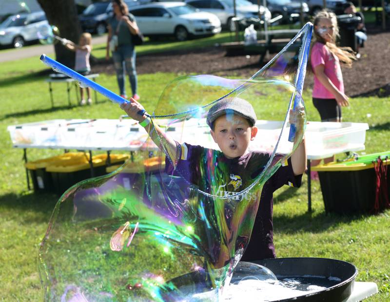 Lars Watts, 4, of Baileyville, blows air to create a big bubble at German Valley Days on Saturday, July 19, 2025. The "Bubble Guy", Jason Kollom of Niles, provided this kid activity during the festival.