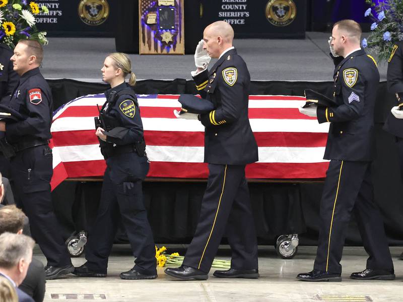 Members of law enforcement salute as they file by the casket of fallen colleague DeKalb County Sheriff’s Deputy Christina Musil Thursday, April 4, 2024, during her visitation and funeral in the Convocation Center at Northern Illinois University. Musil, 35, was killed March 28 while on duty after a truck rear-ended her police vehicle in Waterman.