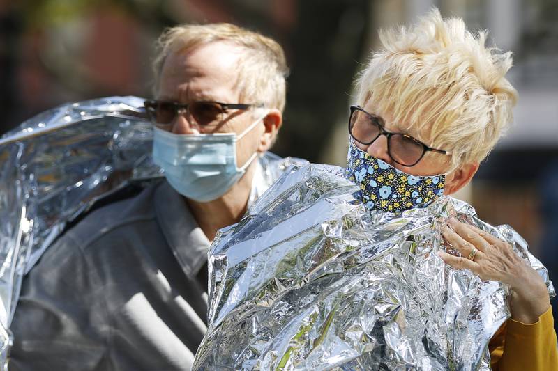 McHenry County Board member Paula Yensen, right, and husband Mike Dissett cover themselves with a mylar sheet as a symbolism and in solidarity with U.S. Immigration and Customs Enforcement detainees who are issued the same thin blankets. Four McHenry County board members were in attendance at the rally to end McHenry County's contract with ICE on Saturday, May 1, 2021, in Woodstock.