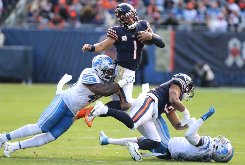 Chicago Bears quarterback Justin Fields picks up yardage before being brought down by Detroit Lions linebacker Jarrad Davis and cornerback Jeff Okudah during their game Sunday, Nov. 13, 2022, at Soldier Field in Chicago.