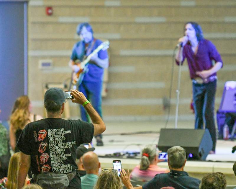 Robert Harris of Wheaton wears a Rolling Stones 2024 tour shirt while video taping Rocks Off: A Tribute to The Rolling Stones on Friday Aug. 2, 2024, held at Memorial Park in Wheaton.