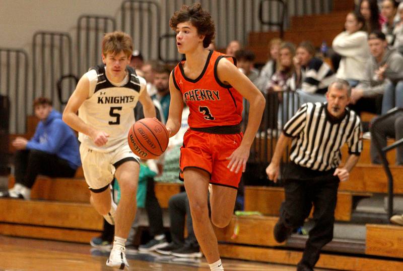 McHenry’s Marko Stojich breaks with the ball as Kaneland’s Bradley Franck, left, pursues the action in Hoops for Healing basketball tournament championship game action at Woodstock Wednesday.