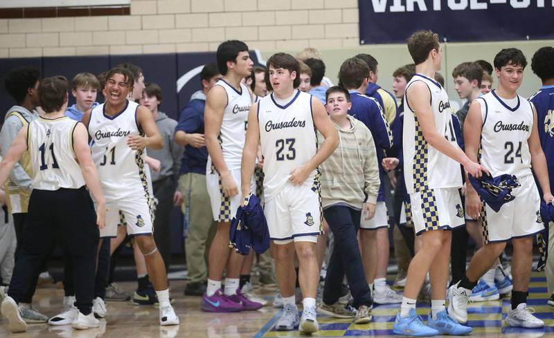 Members of the Marquette boys basketball team celebrate their victory with super fans after defeating Seneca on Friday, Feb. 21, 2025 in Bader Gym at Marquette Academy.