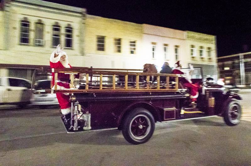 Santa Claus waves off the back of an antique fire engine as it drives through downtown Polo during today's Polo Christmas Festival. The event featured a Christmas tree lighting, horse-drawn carriage rides, photos with Santa and Mrs. Claus and a coloring contest.