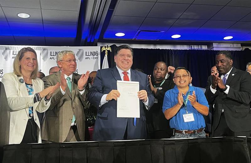 After signing legislation aimed at curtailing the practice of what sponsors dubbed “captive audience meetings,” in which workers are required to listen to their employer’s religious or political views, Gov. JB Pritzker poses with the bill at the Illinois AFL-CIO's biennial convention in Rosemont on Wednesday. Pritzker is flanked by AFL-CIO's national president Liz Shuler and the state organization’s president Tim Drea (left) and state Rep. Marcus Evans, D-Chicago (right), along with other proponents of the bill.