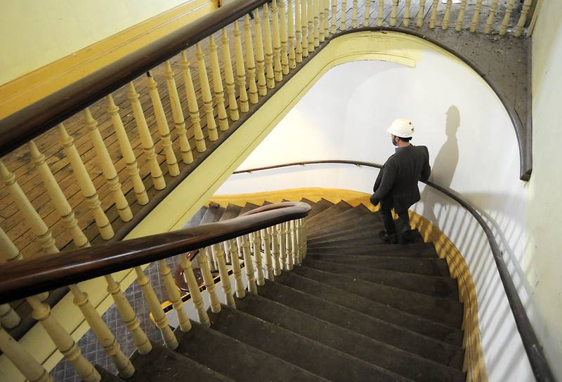 Woodstock City Planner Darrell Moore walks down the old staircase in the Old Courthouse and Sheriff’s House on March 1, 2022, in Woodstock. Workers from Bulley & Andrews, a Chicago-based contractor, have started construction and demolition on the building as part of a renovation project.