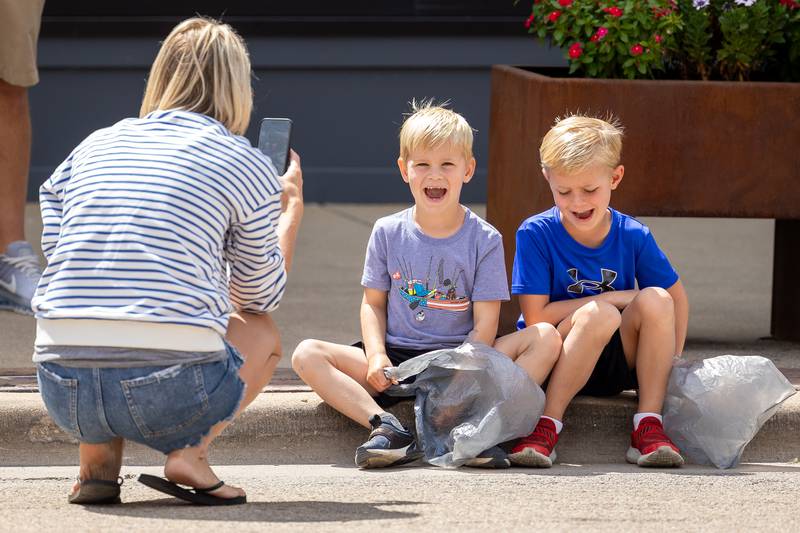 (from left) Megan Hays takes photos of sons, Jace and Jameson Hays sitting on curb on Sunday, Aug 31, 2025 at the Labor Day parade on Main Street in Streator.