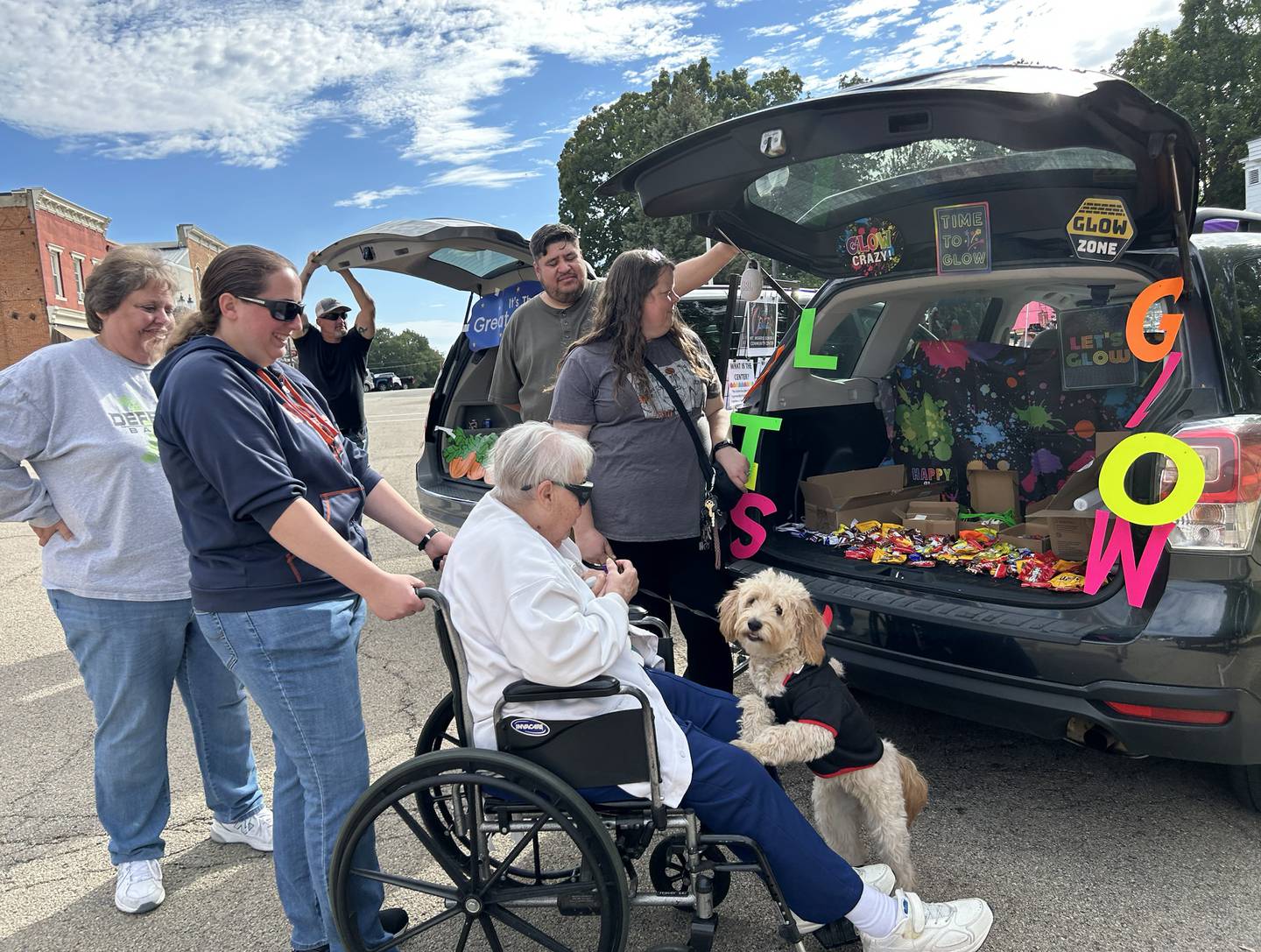 The Kalnins family visited Melissa Rojas and her pup as they got some treats from the Mt. Morris Senior & Community Center during Let Freedom Ring's Fall Family Festival trunk or treat on Sunday, Oct. 12, 2025. The downtown event also included a car show and kids' games..