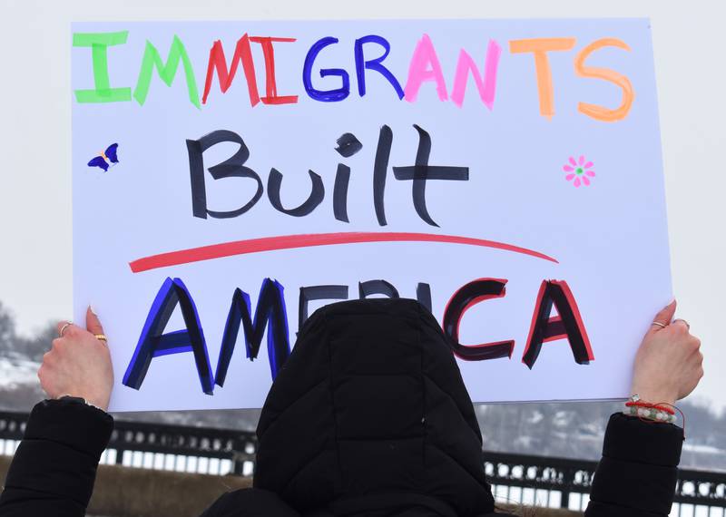 A protestor holds up a sign declaring "Immigrants Built America" during a protest Saturday, Feb. 15, 2025, on the First Avenue bridge between Sterling and Rock Falls.