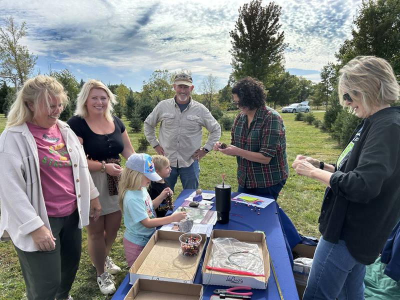 George and Olivia Creamean, ages 4 and 6, turned a pine cone into a Christmas ornament with the help of Illinois Extension Master Gardeners Sara Pohl and Leslie Ciaccio when they visited Ponto Ranch during the Ogle County Farm Stroll with their family on Sunday, Oct. 12, 2025.