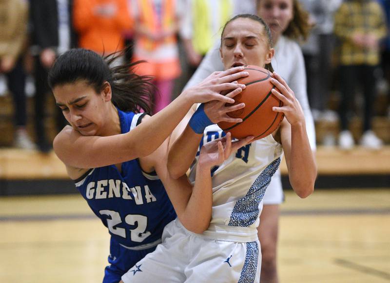 Geneva's Leah Palmer (22) and St. Charles North's Laney Stark wrestle for the rebound during Thursday’s girls basketball game in St. Charles.