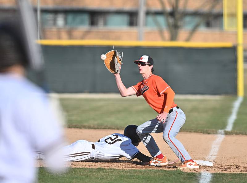 Minooka's Noah Munson attempts to tag the runner on first base during the non-conference game against Joliet Catholic on Monday, March. 11, 2024, at Joliet.