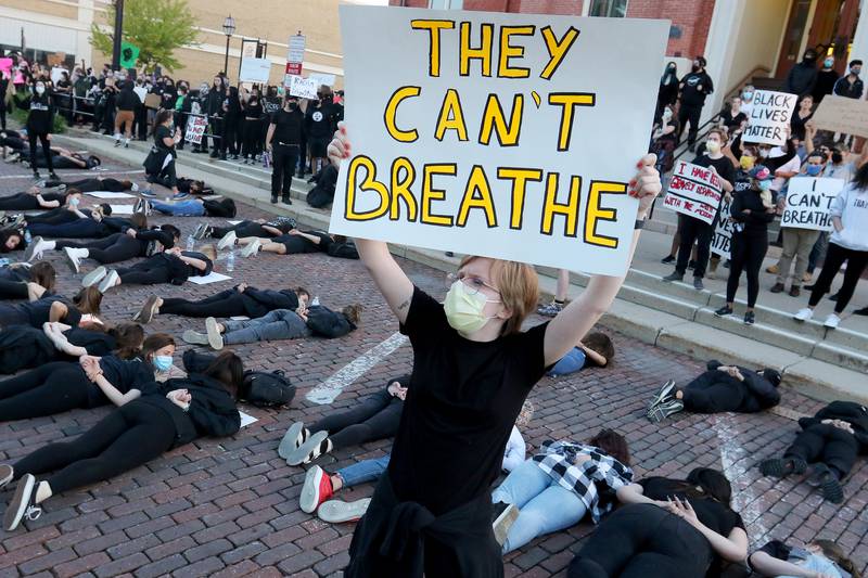 Maggie Morris of Hebron, 19, holds a sign reading "They can't breathe" high in the air as protesters lay in the road with their hands behind their backs, a situation that resulted in the death of George Floyd, outside of the old courthouse during a Black Lives Matter protest to rally against social injustices faced by African-American communities across the nation on the historic Woodstock Square on Sunday, May 31, 2020 in Woodstock.