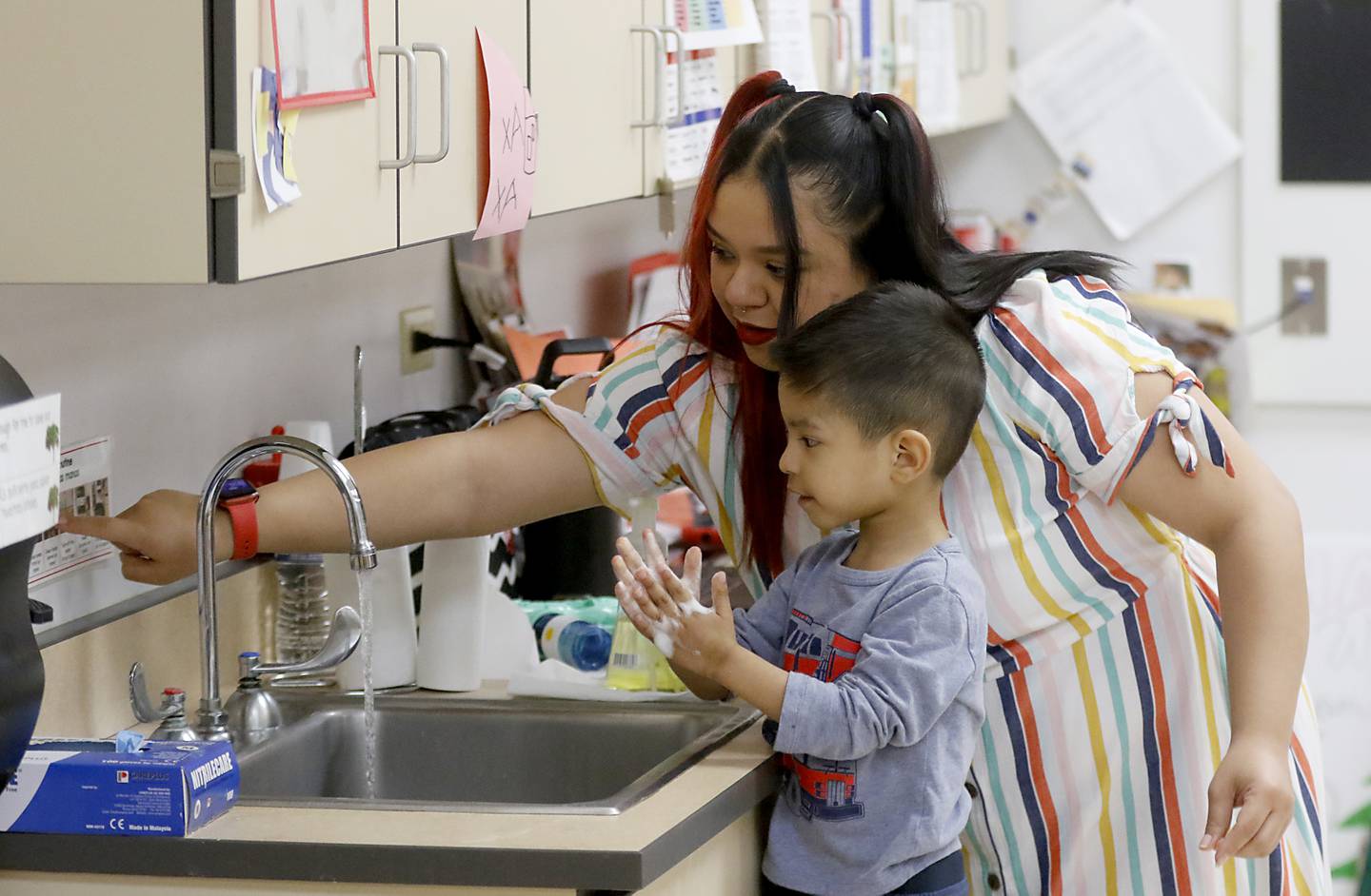 Yasmin Villamar helps a student wash his hands Thursday, April 20, 2023, at the deLacey Family Education Center in Carpentersville.