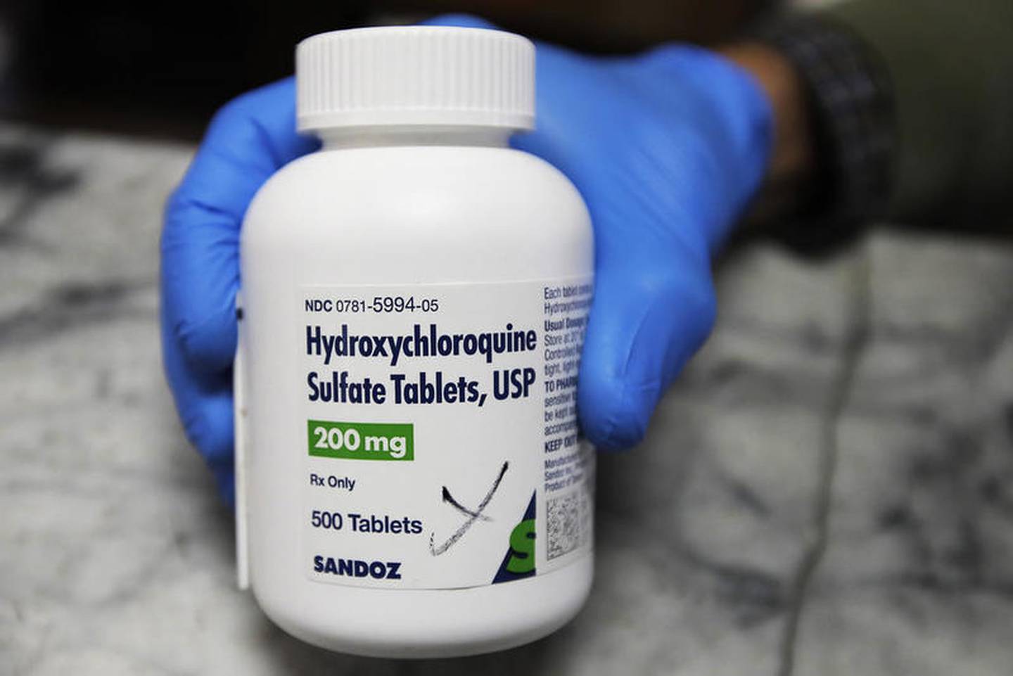 FILE - In this April 6, 2020 file photo, a pharmacist holds a bottle of the drug hydroxychloroquine in Oakland, Calif. Results published Wednesday, June 3, 2020, by the New England Journal of Medicine show that hydroxychloroquine was no better than placebo pills at preventing illness from the COVID-19 coronavirus. The drug did not seem to cause serious harm, though - about 40% on it had side effects, mostly mild stomach problems. (AP Photo/Ben Margot)
