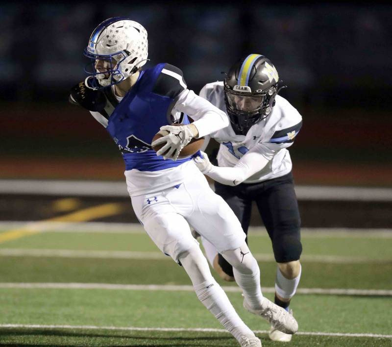 St. Charles North's Zach Priami (11) gets a tug from Maine West’s Jason Hidan (13) Friday October 28, 2022 in St. Charles.