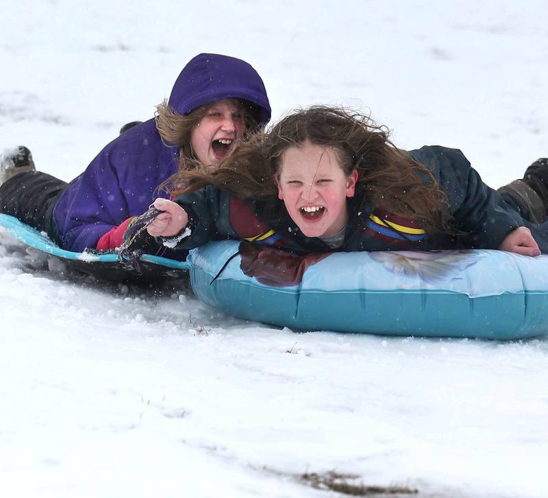 Natalie Sutter, (left) 12, from DeKalb, and Katie Buck, 10, from Sycamore, take a ride down the DeKalb Park District sled hill Wednesday, Jan. 25, 2023, at Hopkins Park in DeKalb.