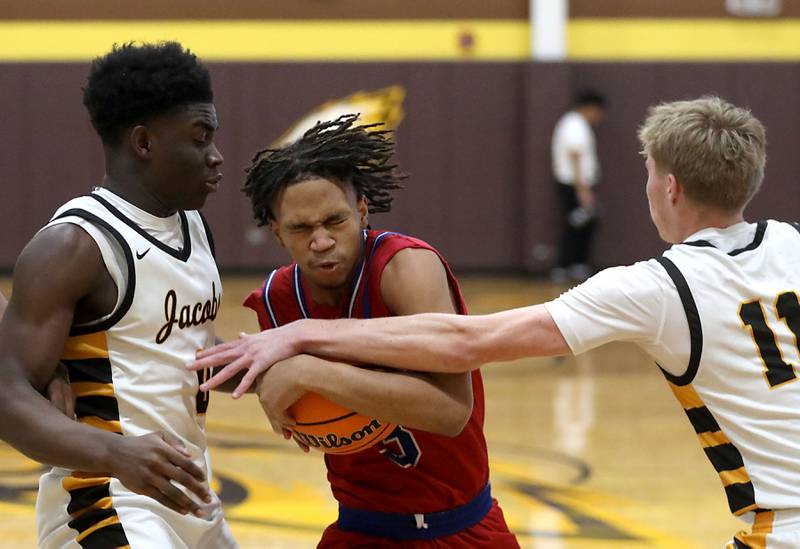 Dundee-Crown's Rasheed Trice tries to drive between Jacobs' Samson Averehi (left) and Carson Goehring (right) during a Fox Valley Conference boys basketball game on Tuesday, February. 3, 2026, at Jacobs High School in Algonquin.