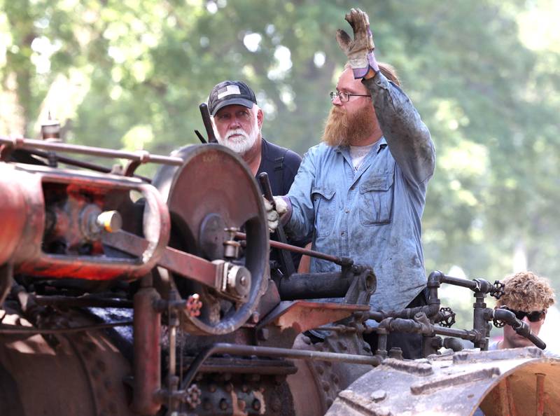 A steam tractor driver waves to spectators Thursday, Aug. 8, 2024, during the 67th annual Sycamore Steam Show and Threshing Bee at Taylor Marshall Farm.
