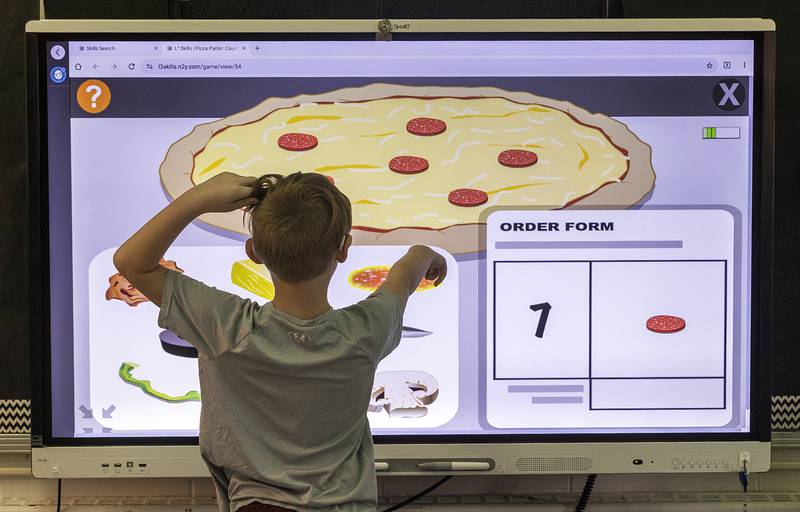 A student picks pepperonis for a counting game Friday, Feb. 7, 2025, on a Jefferson School smart board.