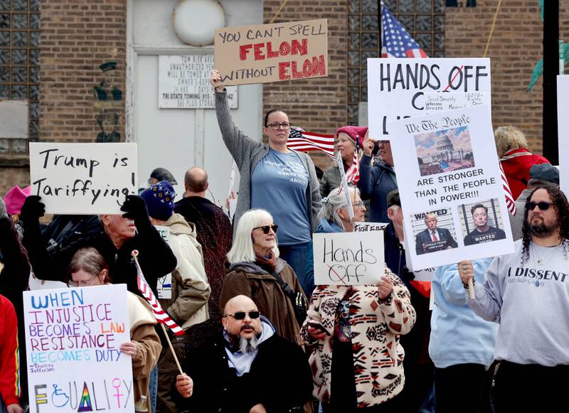 Protesters with various signs assembled Saturday, April 5, 2025, for a Hands Off! rally at Memorial Park on the corner of First Street and Lincoln Highway in DeKalb. The group gathered to protest against various policies of President Donald Trump and his administration.