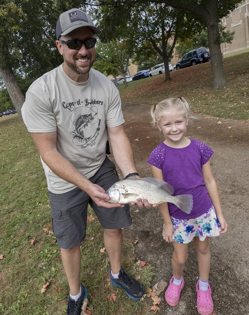 Dixon Police officer Brad Dempsey helps Laney Christen, 8, of Polo, shows off the one pound sheepshead she caught Saturday, Sept. 20, 2025, in Dixon.