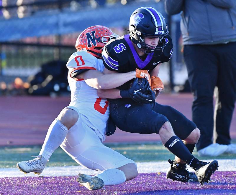 Downers Grove North's Owen Thulin (5) makes a touchdown catch as he is hit by Normal Community's Aiden Boundy (0) during an IHSA Class 7A semifinal game on Nov. 18, 2023 at Downers Grove North High School in Downers Grove.