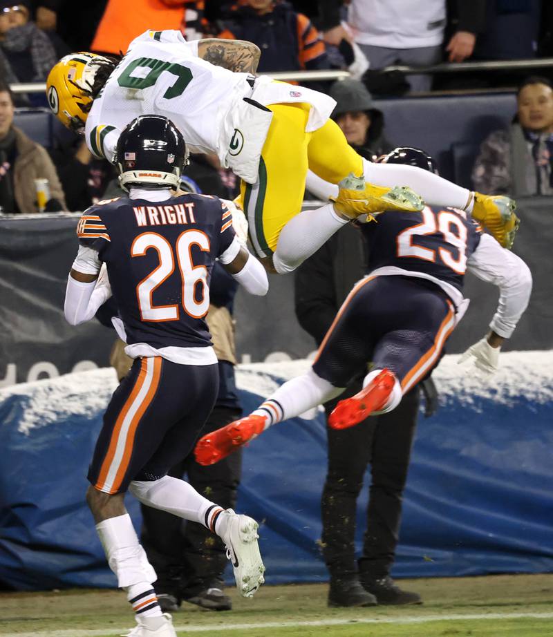 Green Bay Packers wide receiver Christian Watson tries to leap over Chicago Bears cornerback Nahshon Wright and cornerback Tyrique Stevenson during their NFL Wild Card game Saturday, Jan. 10, 2026, at Soldier Field in Chicago.