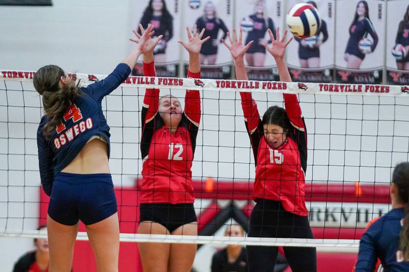 Yorkville's Madeline Hilker (12) and Maggie Konicek (15) defend the net against a kill attempt by Oswego’s Mia Jurkovic (14) during the Class 4A Yorkville Regional final at Yorkville High School on Thursday, Oct. 31, 2024.