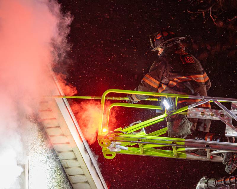 Firefighters standing outside front door of a '2nd Alarm' house fire point towards flame on Saturday, January 10, 2026, at 217 West Delvin Street in Spring Valley.