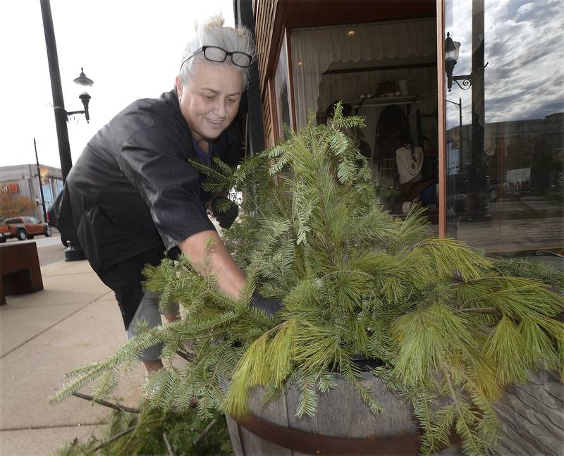 Sadie Kirk, owner of Flowers Plus, creates a holiday display in front of her store during Streator’s Mistletoe Market Saturday .