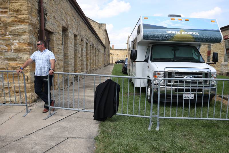 Joliet Detective Anton “Tony” Lakota stands guard as Dan Aykroyd’s Blues Brother suit hangs on a fence at his trailer at the Blues Brothers Con 2022 at the Old Joliet Prison. Friday, Aug. 19, 2022, in Joliet.
