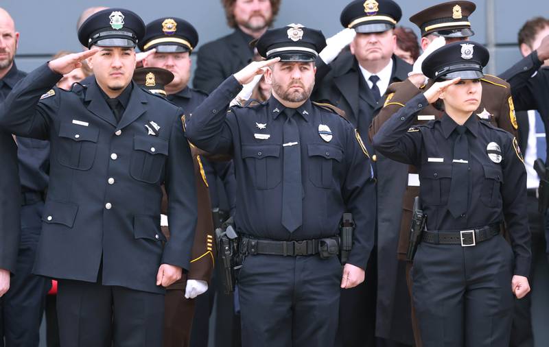 Law enforcement officers salute Thursday, April 4, 2024, outside the Convocation Center at Northern Illinois University, as the casket of DeKalb County Sheriff’s Deputy Christina Musil is brought out following her visitation and funeral. Musil, 35, was killed March 28 while on duty after a truck rear-ended her police vehicle in Waterman.