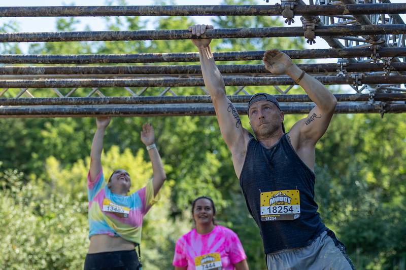 Participates of the 2025 Muddy Dash race across monkey bars on Saturday, June 28, 2025 at Fox Valley Off Road in Utica.